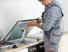 Appliance repair technician installing a built-in cooktop in Charleston, SC