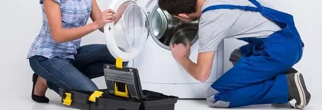 Washer repair technician inspecting a front-load washing machine with tools in Charleston, SC