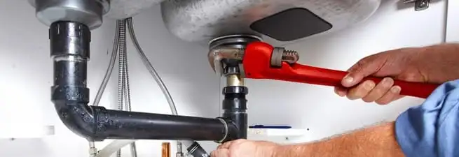 Garbage disposal repair technician tightening the sink drain and disposal connection in Charleston, SC