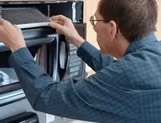 Appliance repair technician replacing a microwave vent filter in Charleston, SC