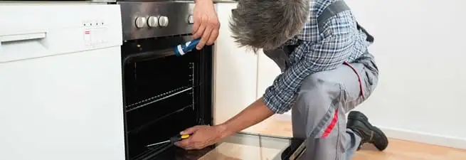 Oven repair technician inspecting and servicing an electric oven in Charleston, SC