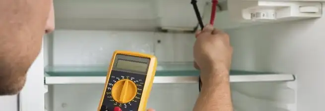 Refrigerator repair technician testing electrical components with a multimeter in Charleston, SC