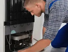 Refrigerator repair technician servicing the compressor and condenser area in Charleston, SC