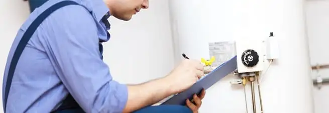 Water heater repair technician inspecting the unit and recording service notes in Charleston, SC