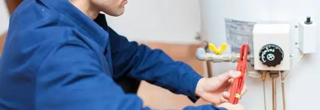 Water heater repair technician adjusting the temperature control and gas valve in Charleston, SC